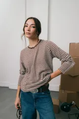 Remera de tejido de punto a rayas horizontales en color marrón y blanco, con cuello redondo, mangas largas y detalle de frunce en el frente.