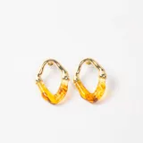 Caravanas de diseño irregular con estructura superior metálica en tono dorado y parte inferior de resina translúcida con efecto marmolado en tonos amarillos y ámbar.