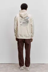 Buzo con capucha y bolsillo tipo canguro, de color crema, con pequeño estampado en el pecho y cordones ajustables en el cuello.