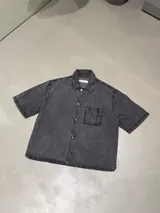 Camisa de jean con lavado gris, corte boxy, manga corta, cuello clásico y bolsillo frontal en el pecho.