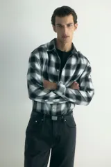 Camisa de franela de algodón suave con estampado a cuadros, cuello inglés, cierre frontal de botones, mangas largas con puños abotonados y bajo redondeado.