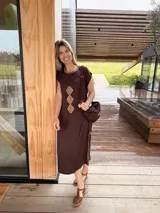 Vestido midi marrón oscuro de corte recto y mangas cortas, con cuello redondo adornado con costuras decorativas y rombos de cuero camel bordados en el frente. Cuenta con aberturas laterales con detalles de costura a contratono.