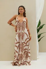 Vestido largo de diseño holgado con estampado geométrico en tonos marrón y blanco, escote halter pronunciado y tirantes finos para anudar al cuello.