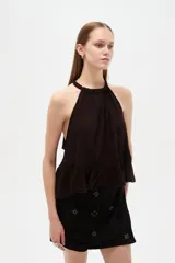 Top blanco de algodón con cuello halter, diseño holgado y detalle de encaje en el borde inferior.