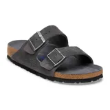 Sandalias Birkenstock modelo Arizona de dos tiras ajustables con hebillas metálicas. Confeccionadas en gamuza color gris carbón, cuentan con la clásica plantilla de corcho anatómica y suela de goma negra.