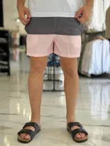 Short de baño con diseño bicolor en tonos gris y rosado, con costuras decorativas visibles en contraste y pequeño aplique circular en el lateral.