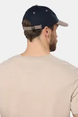 Gorro tipo gorra con visera de lona color azul, con parche tejido frontal que presenta diseño de paisaje y mar.