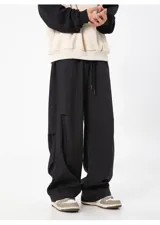 Pantalón cargo negro de corte ancho y holgado, con cintura elástica y cordón ajustable. Presenta detalles de corte o solapa en la parte trasera de las pantorrillas.