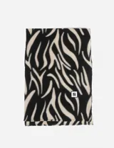 Bufanda rectangular con estampado animal print de cebra en blanco y negro, con detalle de etiqueta cuadrada con logo en el extremo inferior.