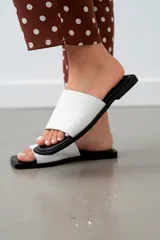 Sandalias de cuero color blanco con suela plana color negro.