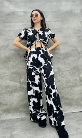 Pantalón palazzo con estampado de flores negras y blancas, de tiro alto y corte holgado.