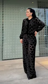 Pantalón de corte recto y tiro alto, confeccionado en terciopelo negro con un diseño calado geométrico que revela una capa inferior transparente. Presenta una cintura elástica para mayor comodidad.