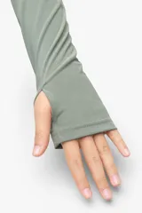 Campera deportiva gris de corte entallado, con cuello alto, cierre frontal completo y mangas largas con ojal para el pulgar.