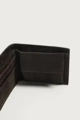 Billetera de piel con acabado en serraje color marrón oscuro, de diseño compacto con detalle de costura horizontal en el centro. Cuenta con compartimento para billetes, ranuras para tarjetas y monedero con cierre de clip.