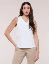 Chaleco blanco sin mangas de estilo smart-casual, con escote en V y costuras verticales de entalle. Cuenta con bolsillos o solapas simuladas a los lados de la cintura decorados con un botón metálico dorado y un largo a la cadera.