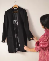 Tapado negro de lana y cashmere, de corte recto y largo a la rodilla, sin botones frontales. Tiene puños cruzados con botones dorados.