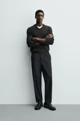 Pantalón de corte regular fit, color negro, confeccionado en tejido elástico. Presenta cintura elástica, cierre frontal con cremallera y botón, bolsillos laterales y bolsillos traseros de vivo.