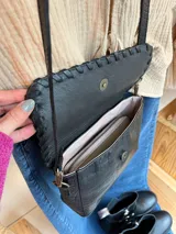 Cartera bandolera de cuero negro con textura tipo cocodrilo, correa larga regulable y forro interno de tela.