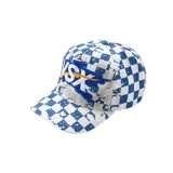 Gorro con visera tipo trucker, con estampado de cuadros estilo damero en azul y blanco, efecto desgastado con salpicaduras y bordado frontal en relieve con letras grandes y un rayo amarillo.