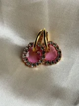 Aros de acero quirúrgico con dije circular de resina rosa y borde de strass dorados.