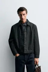 Cazadora de denim de algodón en color negro, de corte regular fit, con cuello solapa, cierre frontal de botones metálicos, mangas largas con puños abotonados y bolsillos laterales de vivo.