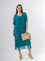 Vestido midi de seda italiana color negro, diseño dos en uno con capa superior de calce amplio, falda con volados y forro interior de algodón elastizado.