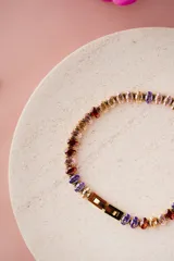 Pulsera de acero quirúrgico con baño de oro, adornada con circonitas de corte ovalado en tonos multicolor.