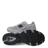 Championes New Balance modelo 509, color gris claro con detalles en gris oscuro y negro. Presentan una combinación de malla transpirable y superposiciones de gamuza, con el logo 'N' en negro en el lateral y suela de goma.