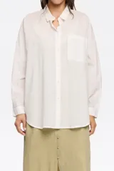 Camisa blanca de corte recto con cierre de botonadura frontal y cuello camisero. Manga larga con puños y botón, bolsillo de plastrón en el pecho y maxicanesú en espalda con logo bordado.