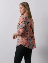 Blusa de gasa estampada con flores, marca Zac & Rachel. Tiene cuello a la base, escote en V y abertura con botones. Las mangas largas son de largo regulable.