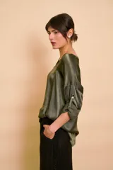 Blusa de satén color verde militar, de corte holgado, con cuello en V y mangas largas con presilla para arremangar.