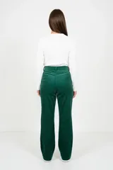 Pantalón de corte recto y tiro alto confeccionado en pana color verde esmeralda. Presenta cintura con trabillas y cinturón del mismo tejido con hebilla forrada, cierre frontal con cremallera y bolsillos laterales.