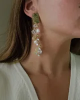 Aros colgantes con base rectangular dorada y cascada de cuentas de cristal, perlas y mostacillas en tonos blanco, dorado y transparente.