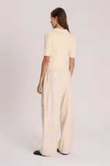 Pantalón babucha color crema de cuero sintético, tipo cargo, con cintura elastizada y lazo de ajuste.