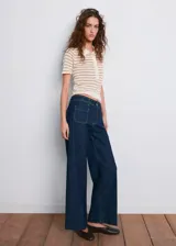 Jeans wide leg de tiro alto en denim azul oscuro, con trabillas para cinto, bolsillos de parche delanteros y cierre frontal de cremallera y botón.