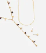 Conjunto de accesorios femenino compuesto por dos collares en capas y un par de aros tipo botón en forma de esfera, en tono dorado. Incluye un collar tipo corbata con abalorios y cuentas oscuras, y una gargantilla de cadena plana tipo cinta.