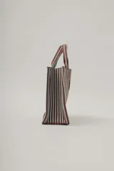 Bolso tote marrón con rayas verticales verde agua. Tiene doble asa corta marrón con rayas verde agua y etiqueta cuadrada con el nombre de la marca en el frente.