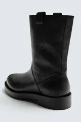 Bota de caña alta confeccionada en piel con acabado granulado y suela de goma con volumen a tono.