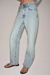Pantalón de jean de tiro bajo y corte recto, con diseño de cinco bolsillos y cierre frontal con cremallera y botón metálico. Presenta un lavado claro.