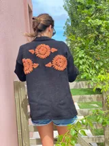 Cárdigan negro de lana merino con bordados de flores color naranja.