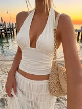Top blanco de tul con diseño halter, escote pronunciado en V y detalles fruncidos en el cuerpo.