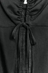 Top largo confeccionado en lino, color negro, con tirantes finos, escote en V con encaje y detalle de frunces y lazada frontal.