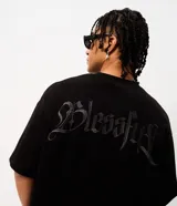 Remera oversize de tejido tipo gamuza sintética negra, con cuello redondo, manga corta y bordado de cruz gótica en el pecho.