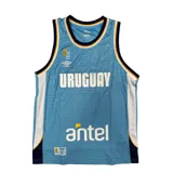 Musculosa de basquet Umbro de la selección uruguaya, color celeste con estampado gráfico sutil en el tejido. Presenta detalles en blanco, azul marino y amarillo en el cuello y sisas, con el logo de Umbro, el escudo de la FUBB y el sponsor Antel estampados en el frente.