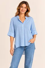 Blusa celeste de corte recto, con cuello mao y escote en V, mangas tres cuartos y diseño holgado.