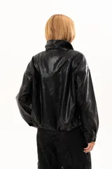 Campera de cuero sintético color negro, con cierre frontal, cuello clásico y bolsillos laterales con broches metálicos.