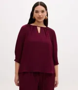 Blusa tipo bata de crepé color bordó, con cuello redondo, detalle de escote en V y mangas 3/4 con fruncidos.