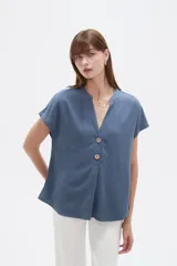 Blusa de viscosa color blanco, de corte holgado, con cuello en V y cierre frontal parcial de botones grandes con efecto carey.