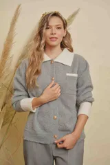 Saco de punto gris con detalles en color crema en el cuello, puños y bolsillo frontal. Presenta cierre frontal con botones y diseño de manga larga.