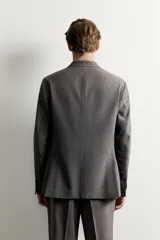 Blazer gris de corte regular fit con patrón a cuadros, confeccionada en tejido con mezcla de lana. Cuenta con cuello de solapa de muesca, cierre frontal de botonadura sencilla, bolsillos con solapa en la cadera, bolsillo de vivo en el pecho y aberturas en la espalda.